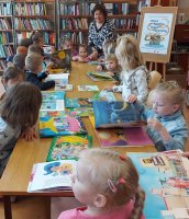 zdjęcie bibliotekarki rozdającej książki dzieciom