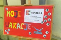 zdjęcie tablicy z napisem moje wakacje, informacji o projekcie mfundacji i logo biblioteki