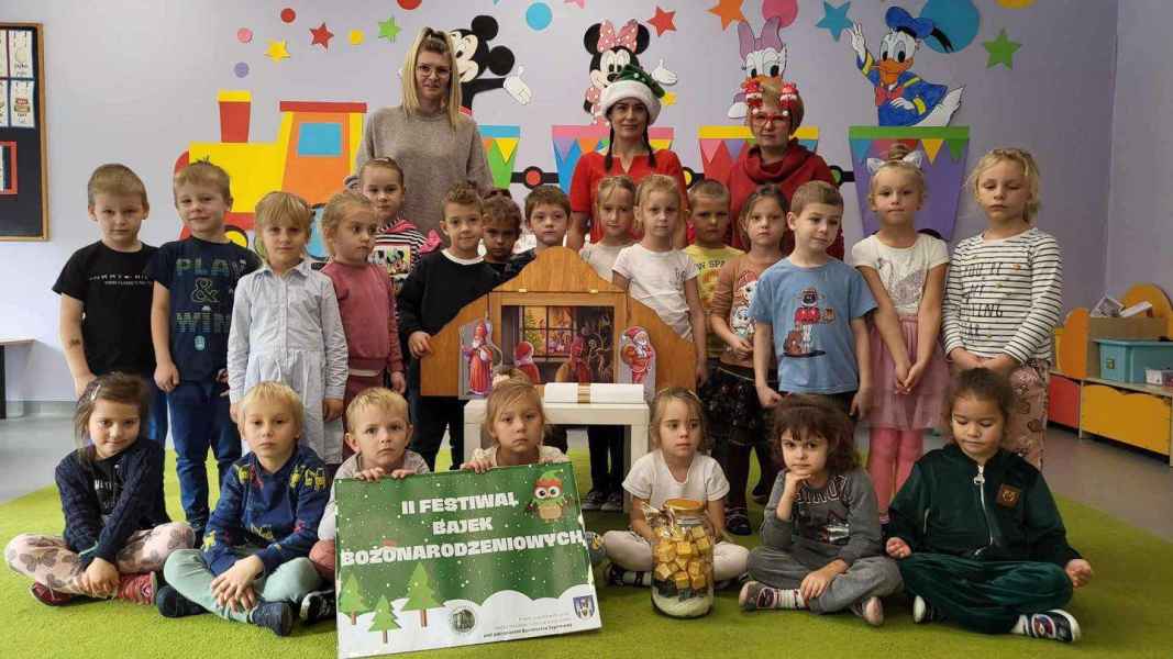 grupowe zdjęcie bibliotekarek z wychowawczynią grupy, przedszkolakami, teatrzykiem kamishibai i plakatem festiwalu