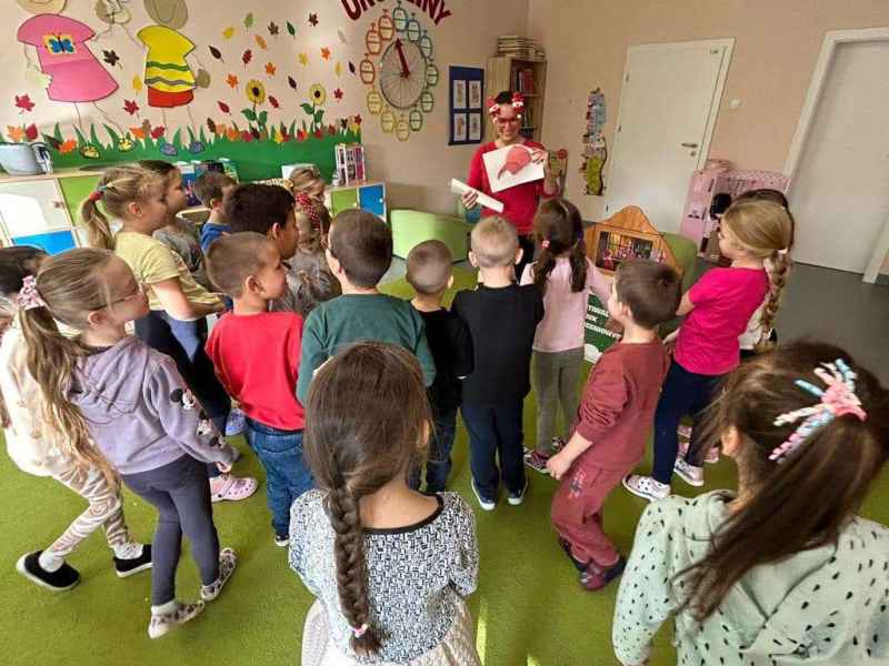 zdjęcie przedszkolaków zgromadzonych wokół bibliotekarki pokazującej im obrazki