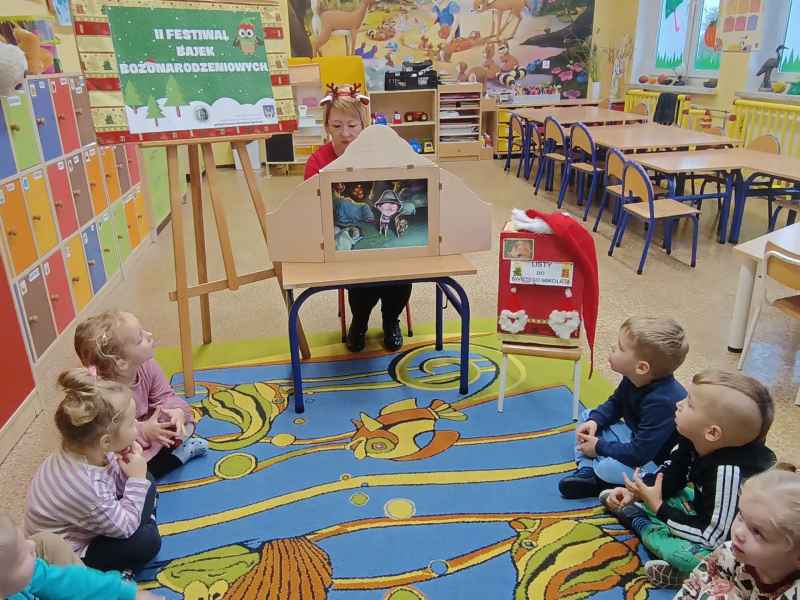 zdjęcie bibliotekarki z teatrzykiem kamishibai oraz dzieci oglądające spektakl