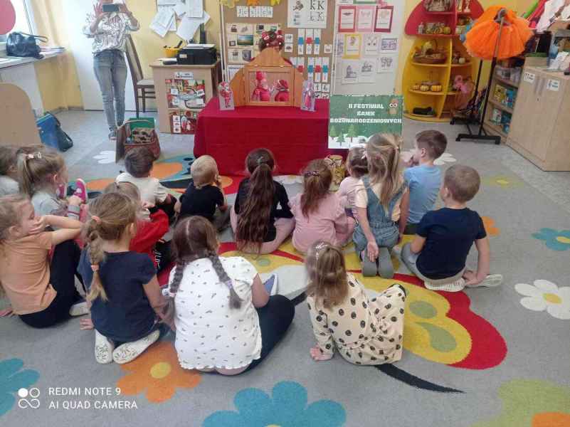 zdjęcie dzieci w trakcie oglądania teatrzyku przedstawianego przez bibliotekarkę