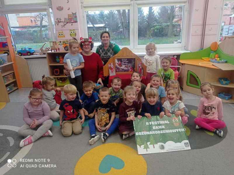 grupowe zdjęcie bibliotekarki, wychowawczyni grupy i przedszkolaków z teatrzykiem i plakatem festiwalu