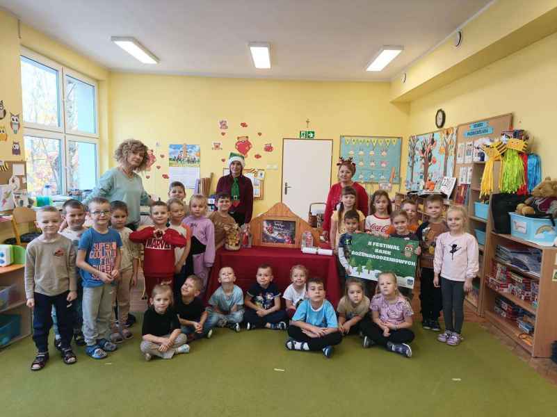 zdjęcie bibliotekarek, wychowawczyni grupy oraz przedszkolaków z teatrzykiem kamishibai i plakatem festiwalu