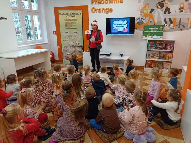 zdjęcie bibliotekarki pokazującej dzieciom zalaminowane obrazki 