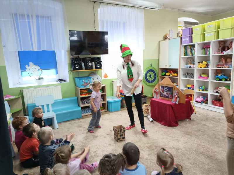 zdjęcie bibliotekarki instruującej dziecko w zadaniu wrzucaniu prezentu do komina