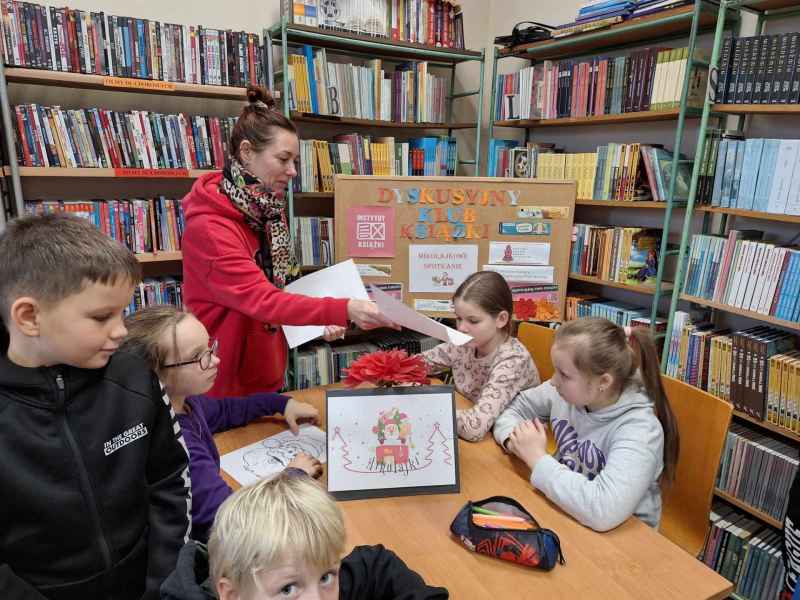 zdjęcie wychowawczyni rozdającej dzieciom mikołajkowe kolorowanki