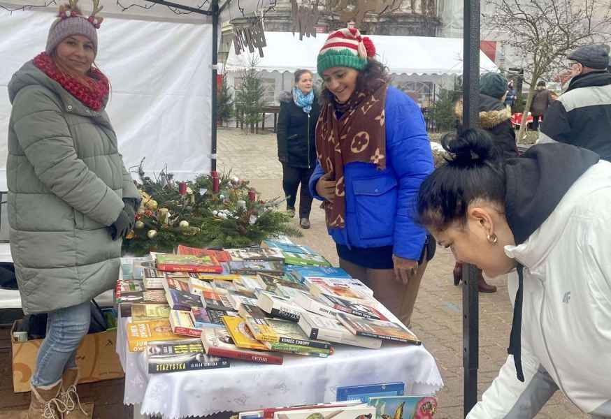 zdjecie bibliotekarki oraz dwóch pań w trakcie oglądania stroików i książek na wystawie