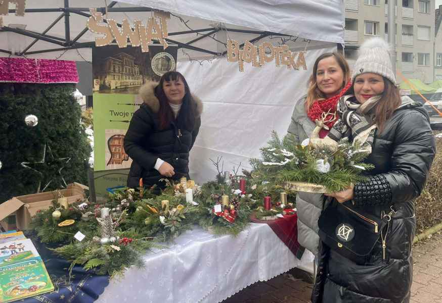 zdjęcie dwóch bibliotekarek i pani z zakupionym stroikiem świątecznym