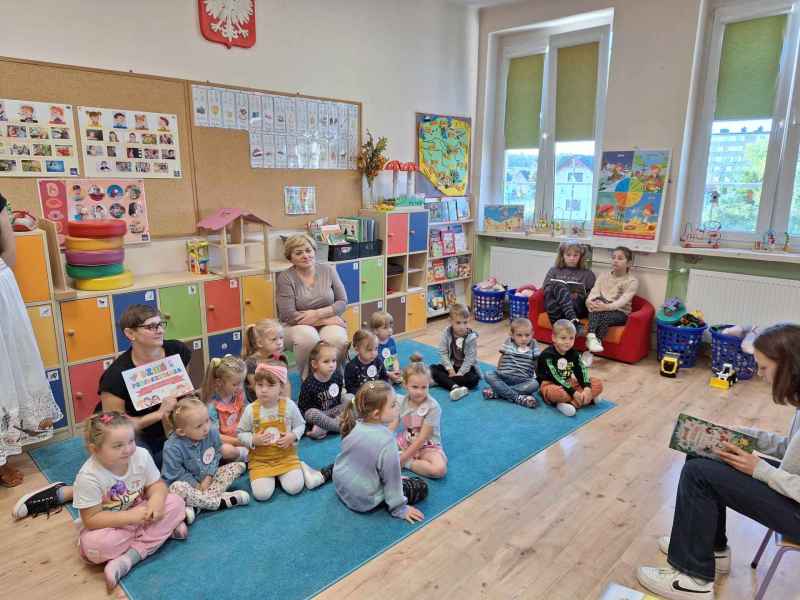 zdjęcie bibliotekarki i wychowawcy wraz z przedszkolakami na dywanie