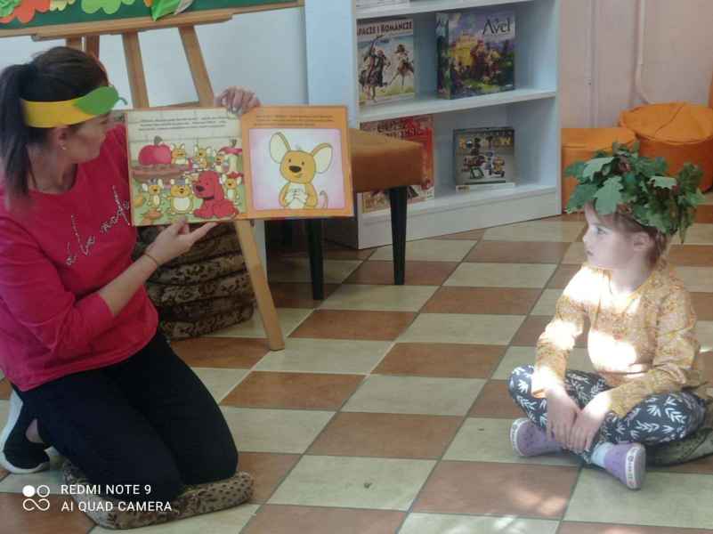 zdjęcie bibliotekarki pokazującej dzieciom rysunki w książce