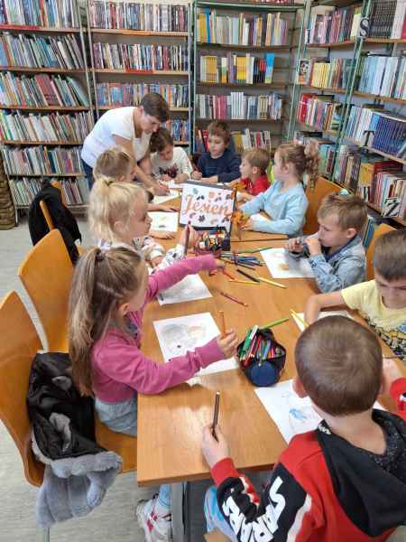 zdjęcie dzieci podczas kolorowania jesiennych obrazków z bibliotekarką