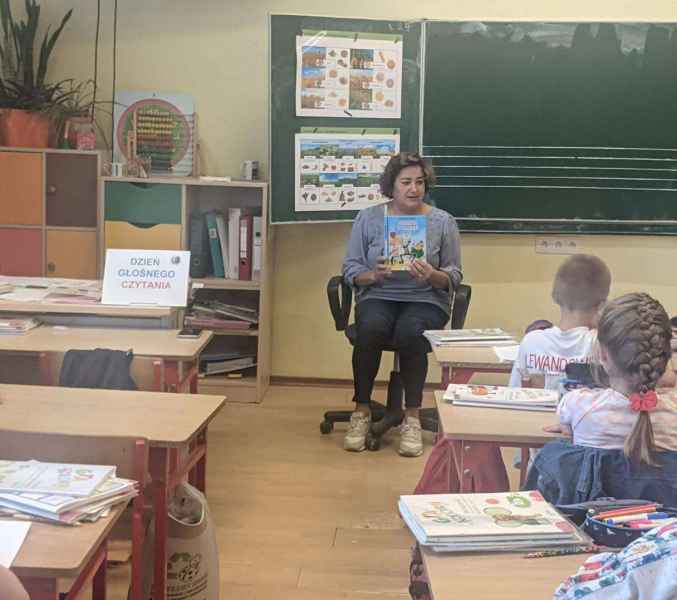 zdjęcie bibliotekarki pokazującej dzieciom okładkę książki