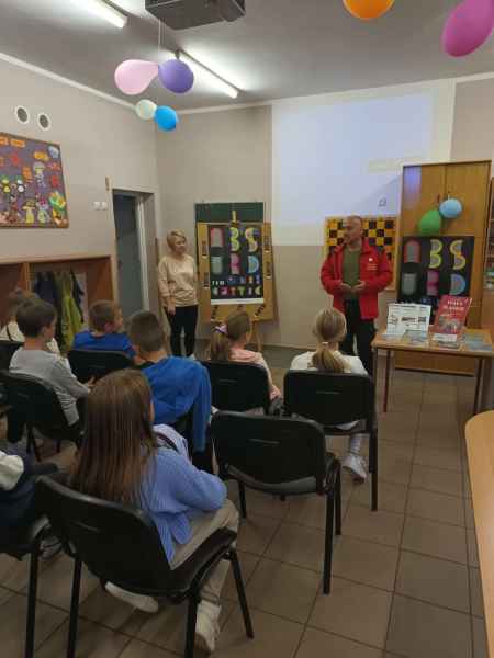 zdjęcie bibliotekarki i pana Macieja Boryny mówiącego do dzieci z klasy