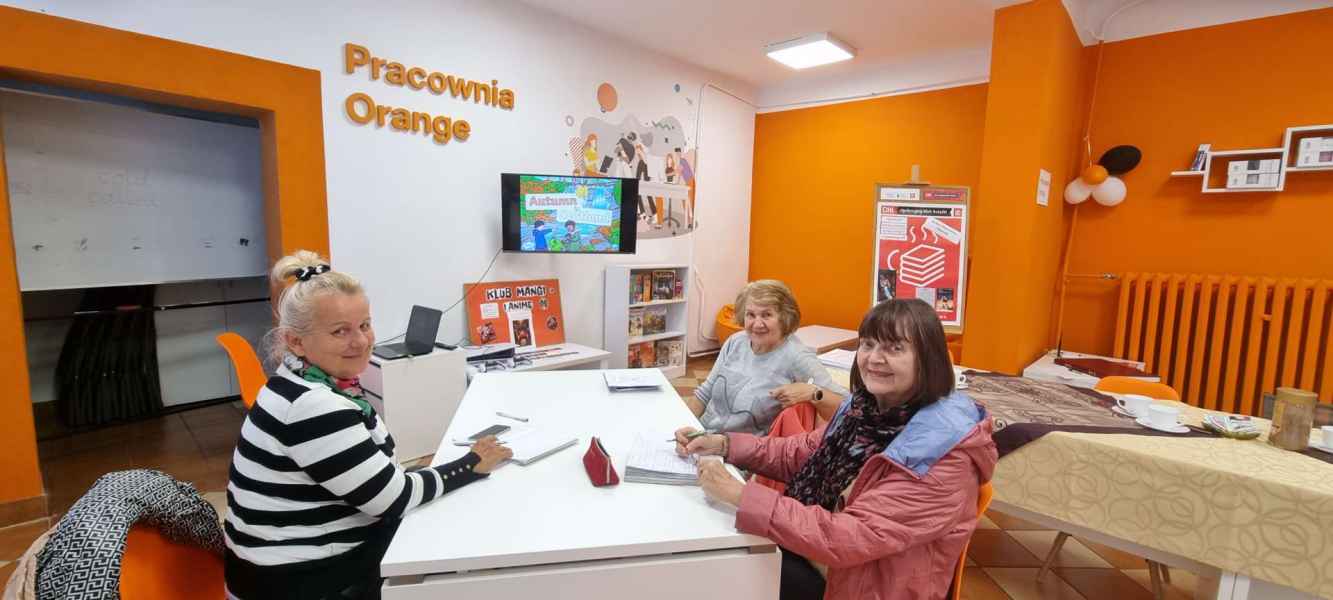 zdjęcie trójki seniorek uśmiechających się do zdjęcia w pracowni orange