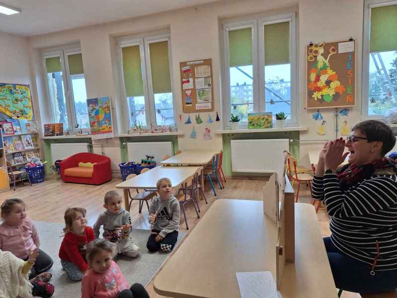 zdjęcie bibliotekarki z teatrzykiem kamishibai i oglądającymi dziećmi