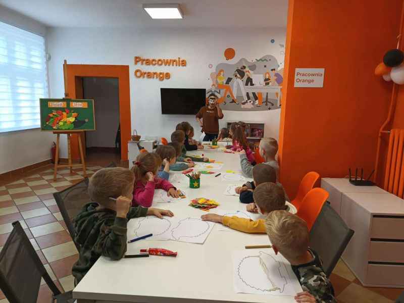 zdjęcie bibliotekarki w masce jeżyka oraz dzieci siedzące przy stołach