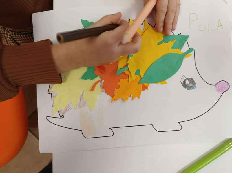 zdjęcie rąk dziecka wyklejających jeżyka w papieru