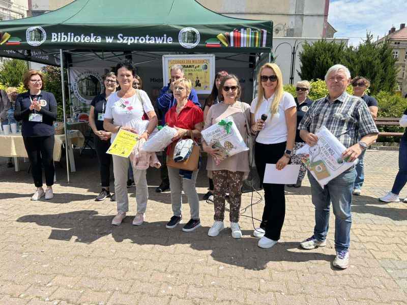 zdjęcie nagrodzonych członków Polskiego Związku Emerytów Rencistów i Inwalidów Szprotawa z dyrektor i pracownikami biblioteki przed namiotem