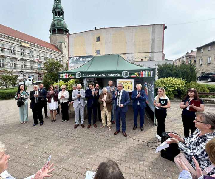 zdjęcie burmistrza Szprotawy, radnych miejskich oraz dyrektor biblioteki i bibliotekarki podczas otwarcia gry miejskiej na tle namiotu biblioteki