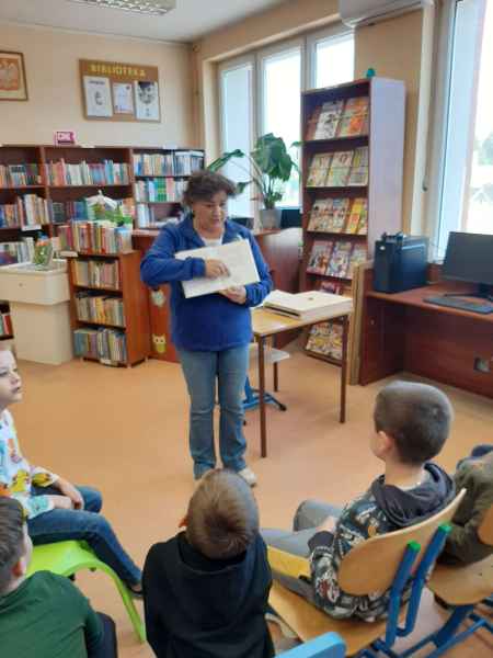 zdjęcie bibliotekarki pokazującej dzieciom książkę