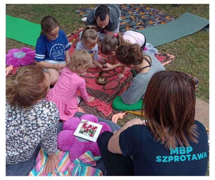 zdjęcie joginki pokazującej dzieciom i rodzicom tybetańską misę grającą