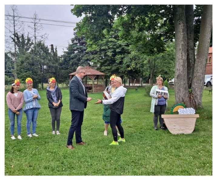 zdjęcie burmistrza wręczającego nauczycielce rekwizyt pieniędzy podczas przedstawienia