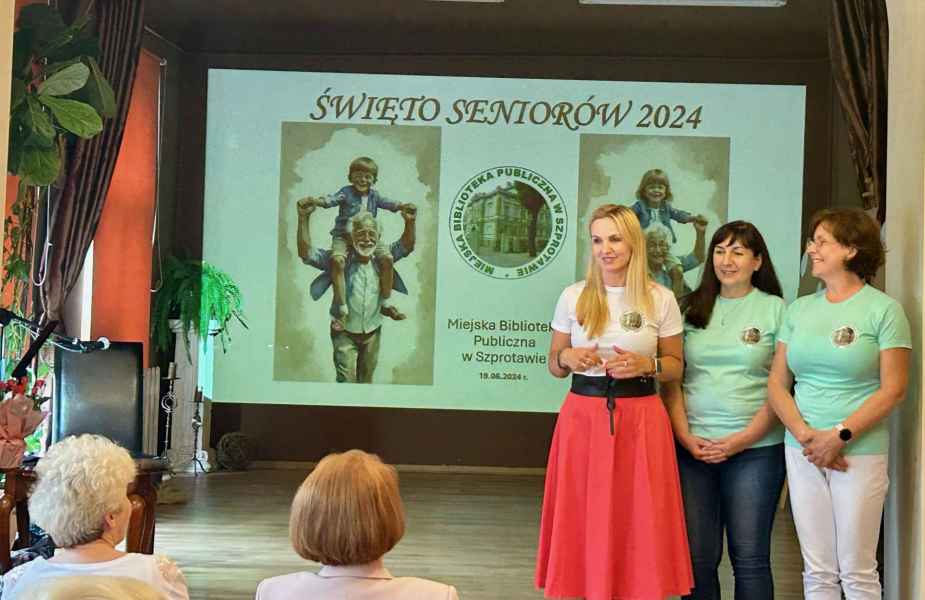 zdjęcie dyrektor i dwóch bibliotekarek podczas przemowy powitalnej na tle slajdu z prezentacji