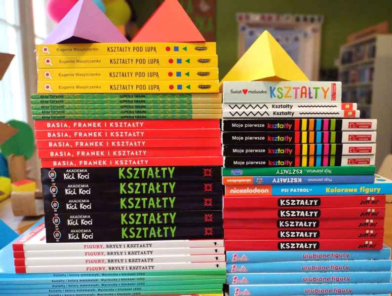 zdjęcie stosów z grzbietami książek o geometrii, na nich bryły geometryczne