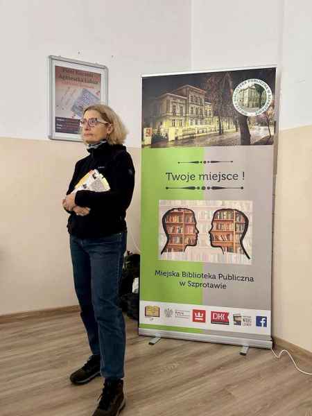 zdjęcie autorki Agnieszki Łabuz z książką na tle baneru biblioteki