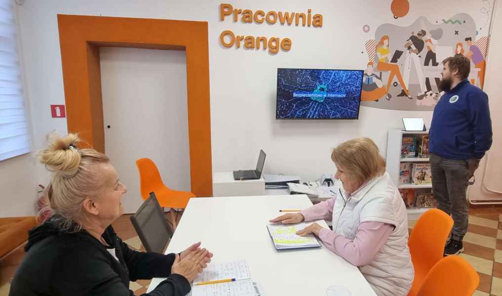 zdjęcie dwóch czytelniczek i informatyka w pracowni orange oglądających prezentację