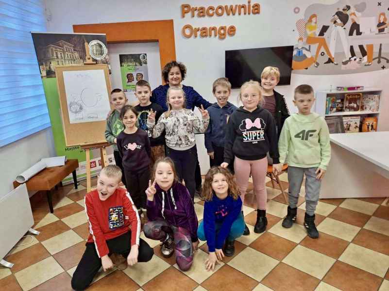 zdjęcie bibliotekarki i dzieci na tle baneru biblioteki