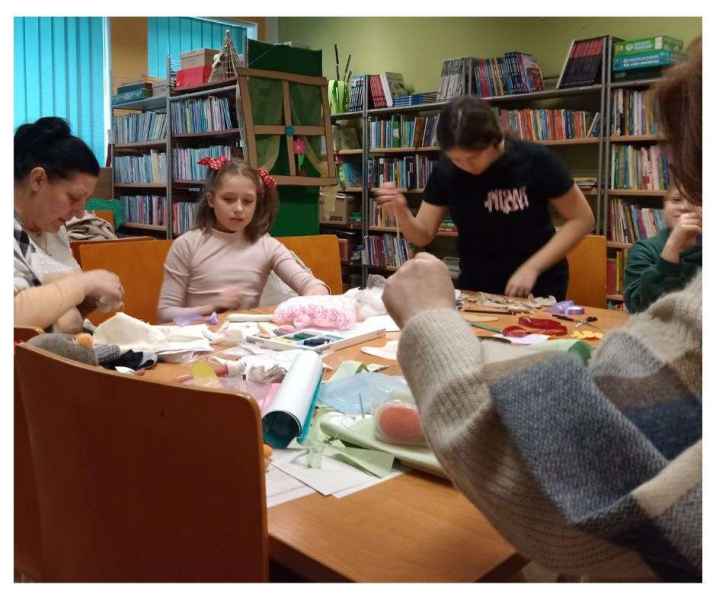 zdjęcie bibliotekarki i czytelników podczas szycia własnych maskotek