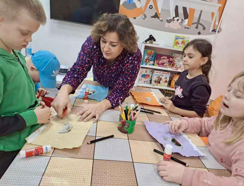 zdjęcie bibliotekarki pomagającej dziecku z pracą plastyczną