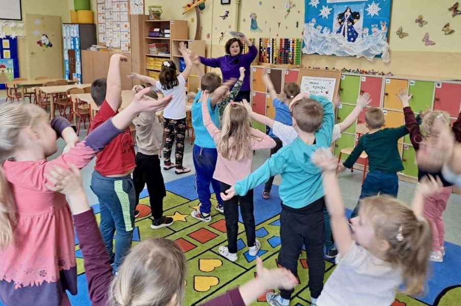 zdjęcie bibliotekarki i dzieci z wyciągniętymi w górę rękoma