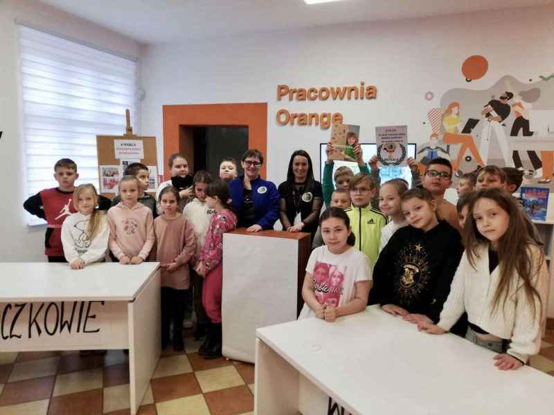 grupowe zdjęcie dzieci oraz bibliotekarek przy stolikach drużyn i pulpicie