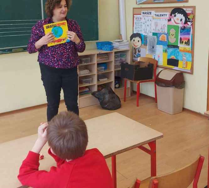 zdjęcie bibliotekarki pokazującej uczniom książkę