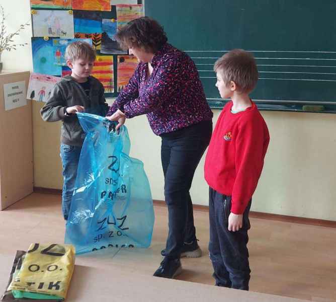 zdjęcie bibliotekarki i dwóch chłopców w trakcie otwierania worków do segregacji odpadów