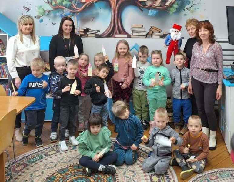 grupowe zdjęcie bibliotekarki, wychowawczyń i dzieci z wykonanymi zakładkami do książek