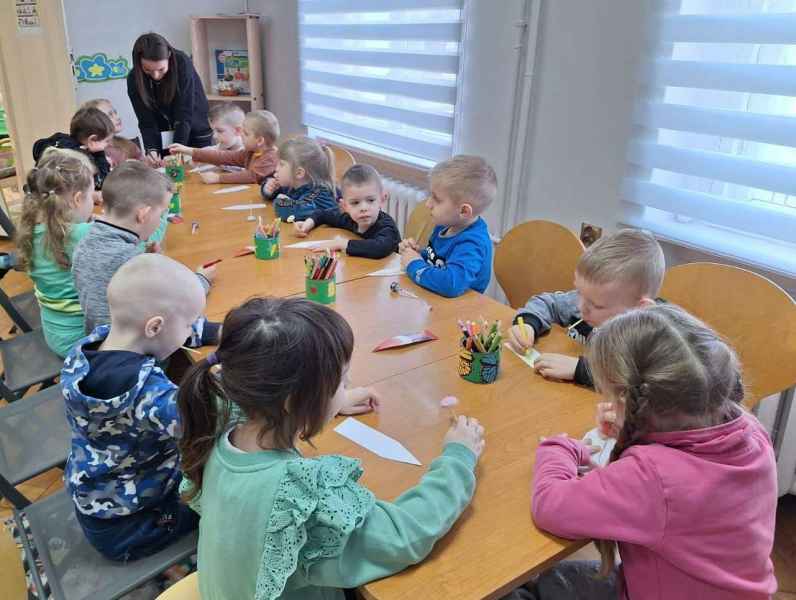 zdjęcie dzieci podczas dekorowania własnych zakładek i pomagająca im bibliotekarka