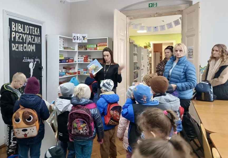 zdjęcie bibliotekarki pokazującej przedszkolakom i wychowawczyniom wyprawki z projektu mała książka wielki człowiek