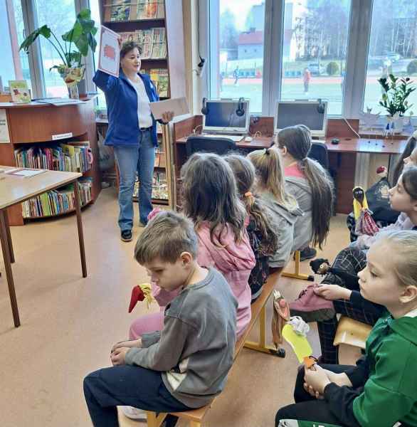 zdjęcie bibliotekarki pokazującej dzieciom na kartach elementy teatru