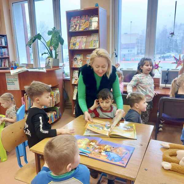 zdjęcie nauczycielki pokazującej dzieciom książkę