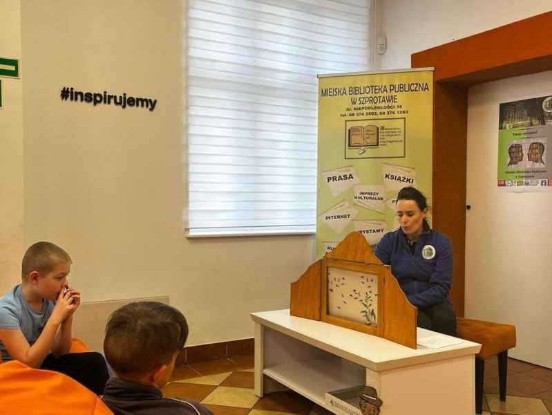 zdjęcie bibliotekarki przedstawiającej dzieciom teatrzyk kamishibai