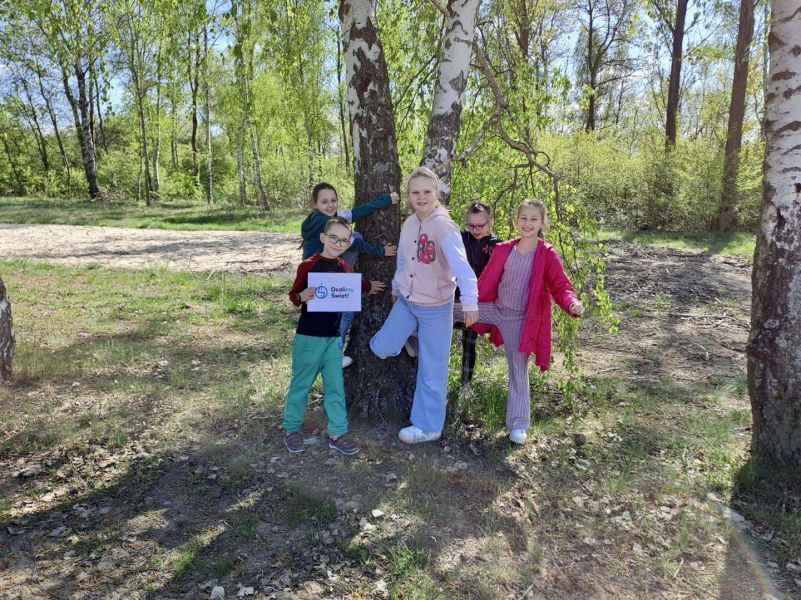 zdjęcie dzieci przy drzewie z kartkaą z logo i napisem ocalimy świat