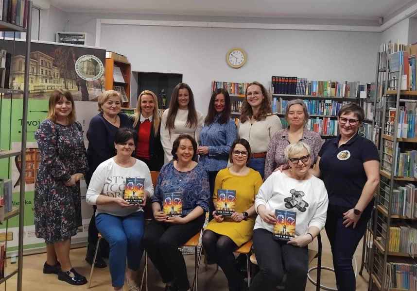zdjęcie grupowe pisarki, dyrektor biblioteki, bibliotekarki i czytelniczek z książkami autorki