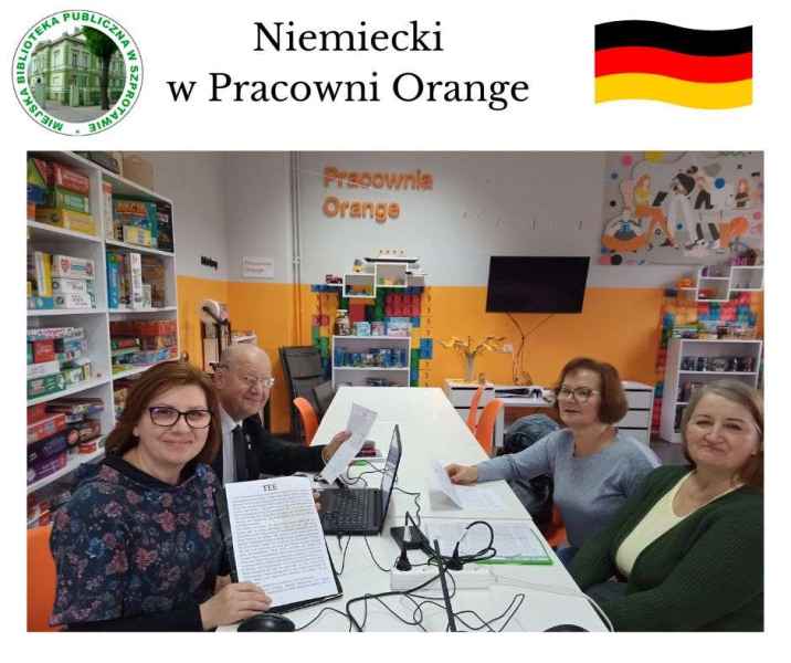 zdjęcie bibliotekarki i kursantów przy stoliku, na górze napis niemiecki w pracowni orange, po lewej logo biblioteki, po prawej grafika flagi Niemiec