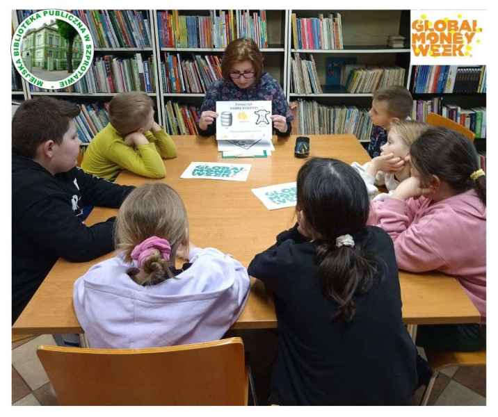 zdjęcie dzieci słuchających bibliotekarki przy stoliku, po prawej logo global money week, po lewej logo biblioteki