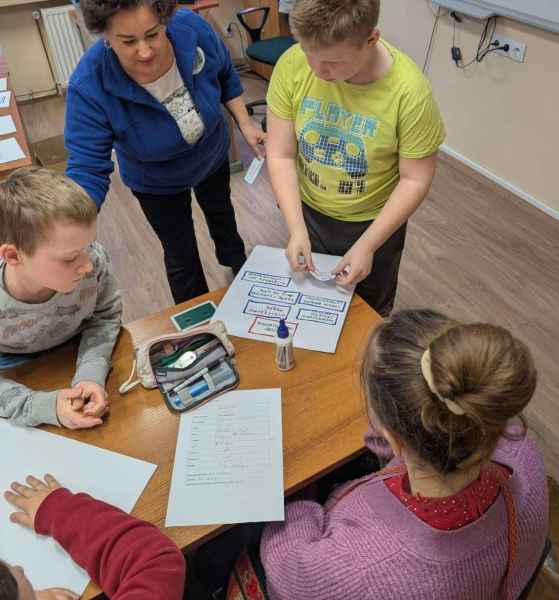 zdjęcie bibliotekarki nadzorującej prace plastyczne dzieci