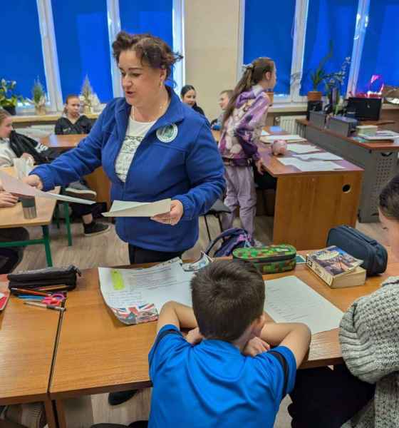 zdjęcie bibliotekarki rozdającej dzieciom kartki papieru